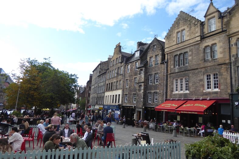 Attractive buildings and people eating outside on the street in Grassmarket.